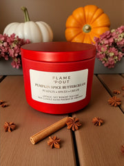 Red candle labeled 'Flame Pout' with pumpkins and cinnamon sticks on a wooden surface