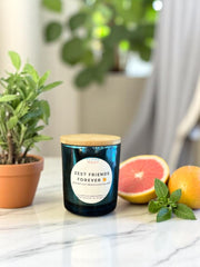 Zest Friends Forever candle surrounded by fresh grapefruit and mint leaves